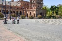 a group of people riding on top of bikes on a brick road in front of an old building