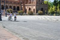 a group of people riding on top of bikes on a brick road in front of an old building