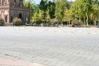 a group of people riding on top of bikes on a brick road in front of an old building