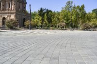 an empty circular paved city plaza with a cathedral in the background and trees behind it