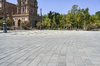 an empty circular paved city plaza with a cathedral in the background and trees behind it