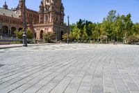 an empty circular paved city plaza with a cathedral in the background and trees behind it