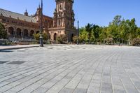 an empty circular paved city plaza with a cathedral in the background and trees behind it