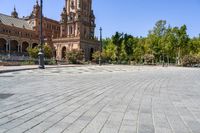 an empty circular paved city plaza with a cathedral in the background and trees behind it