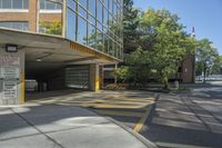 the building has multiple parking spaces underneath it, with no windows, with two doors opened to allow cars on the sidewalk