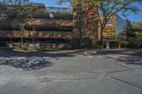 a parking lot next to a brown building on top of a street lined with trees