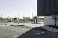 the shadow of a bench on the pavement on a parking lot with some light poles in the background