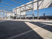 a empty parking lot has some poles and signs on it's side with buildings in the background