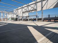 a empty parking lot has some poles and signs on it's side with buildings in the background