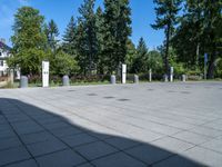 the shadow of a person sits on a concrete ground next to a white building and some trees