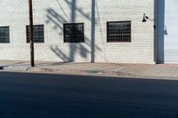 the shadow of a person who is on the sidewalk behind a traffic pole next to an building