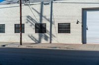 the shadow of a person who is on the sidewalk behind a traffic pole next to an building