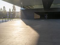 a shadow of someone walking around an empty building in a park with a skateboard