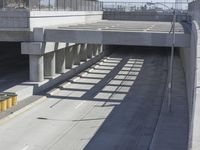 the shadows of two traffic lights on the highway overpasses, and an empty road underneath