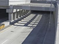 the shadows of two traffic lights on the highway overpasses, and an empty road underneath