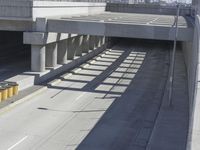 the shadows of two traffic lights on the highway overpasses, and an empty road underneath