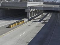 the shadows of two traffic lights on the highway overpasses, and an empty road underneath