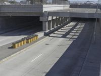 the shadows of two traffic lights on the highway overpasses, and an empty road underneath