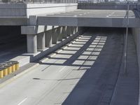 the shadows of two traffic lights on the highway overpasses, and an empty road underneath