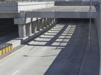 the shadows of two traffic lights on the highway overpasses, and an empty road underneath