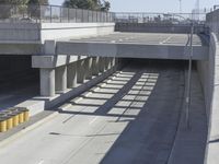 the shadows of two traffic lights on the highway overpasses, and an empty road underneath