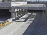 the shadows of two traffic lights on the highway overpasses, and an empty road underneath