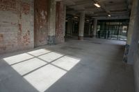 an empty building with a large, sunny room with windows, and bricks all over it