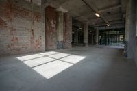 an empty building with a large, sunny room with windows, and bricks all over it