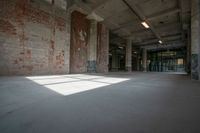 an empty building with a large, sunny room with windows, and bricks all over it