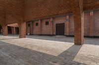 the inside of an empty brick building with red bricks on it and two doors open