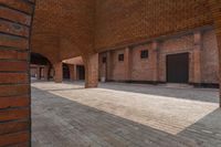 the inside of an empty brick building with red bricks on it and two doors open