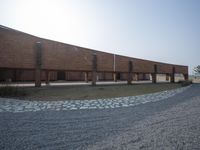 an outside courtyard of a brick building with some benches at the side of it, with a view of the sky