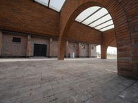 an empty brick building with several windows and arches over it, has a bench on the side