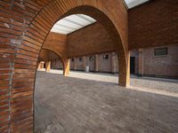 an empty brick building with several windows and arches over it, has a bench on the side