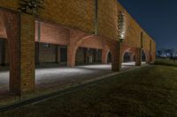 the empty courtyard in an empty building has brick pillars and columns at night, with lights from overhead and in a few different directions