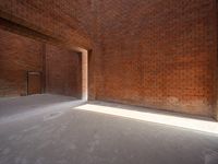 the sun is shining into a brick wall that sits next to a large building with an empty doorway