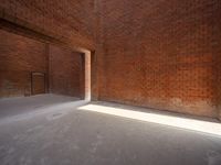 the sun is shining into a brick wall that sits next to a large building with an empty doorway