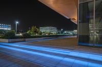 a nighttime view of an office building lit up by a blue streak of light at the end of the walkway