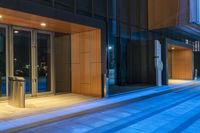 a glass walled building with an outside patio lit up at night to give people a feel