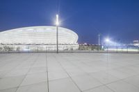 a large building with white pillars in front of a blue sky and the city lights on top