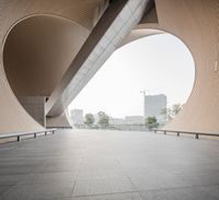 a man riding his skateboard down a cement covered walkway past large building structures and arches