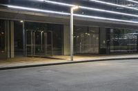 a street light in a building near an empty sidewalk at night time the lights are shining bright