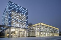 an elegant building is lit up at night with glowing signage and buildings around it that have triangular shaped glass windows