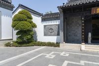 a courtyard at a hotel with white columns and a black doorway with a carved - in figure and a tree with a crown