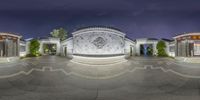 a wide angle photo shows the entrance and the courtyards of a large mansion at night