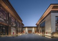 an outdoor view of an building with courtyard seatings and lighting in the evening,