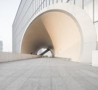 two people are riding on their skateboards through a tunnel as another man stands on the sidewalk, in front of them