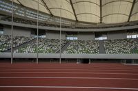 an empty stadium full of people sitting at the stands and on the track, a large round roof and high ceilings