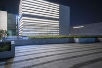 a picture of an empty courtyard with some planters on the floor and an office building behind