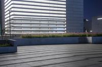 an empty building with plants in the sidewalk, outside, and on top of it